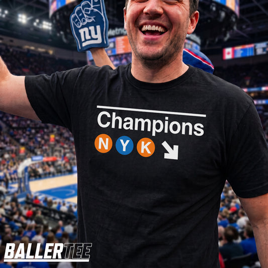 New York basketball 2026 Champions t-shirt in black – NYC subway-inspired graphic with NYK lettering in orange and blue circles by BallerTee
