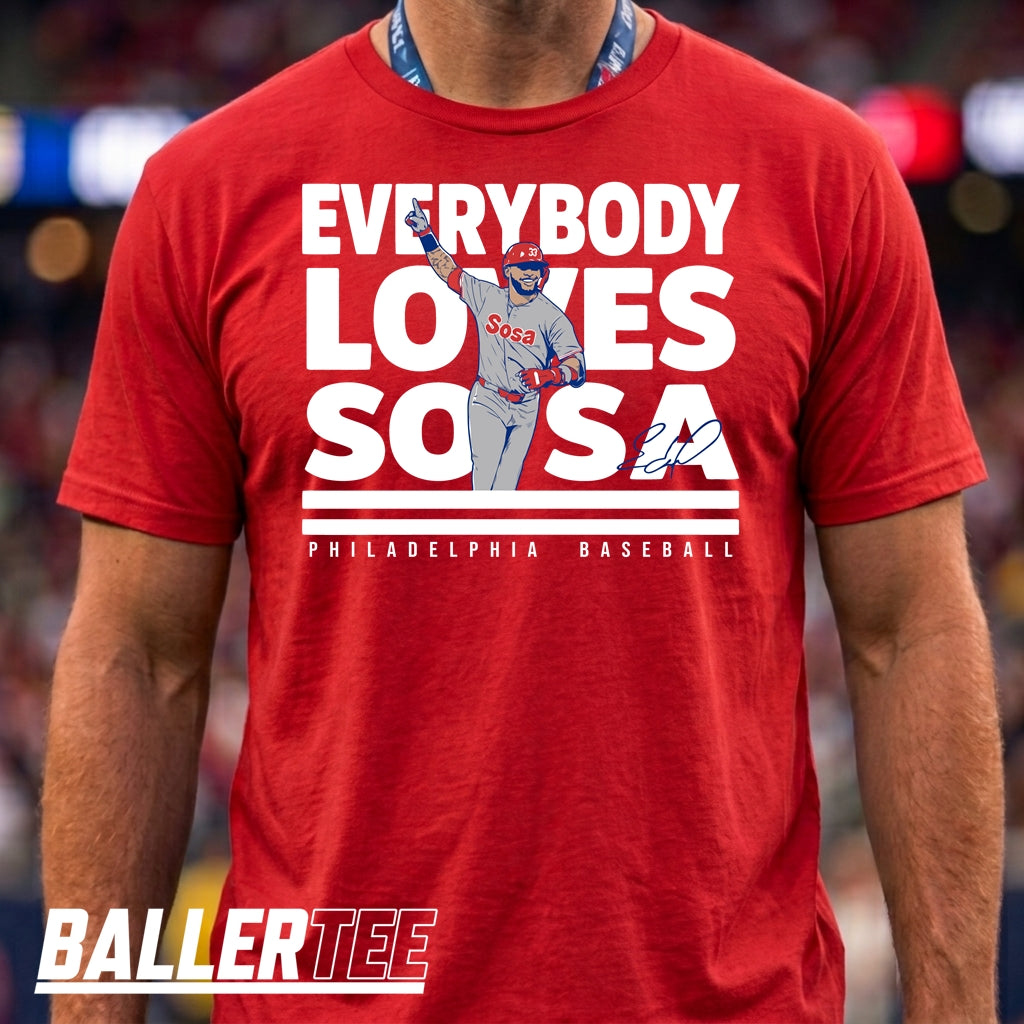 A man wearing a red short-sleeve graphic T-shirt with a large white and blue Philadelphia Baseball 'Everybody Loves SO SA' print on the front. The image is cropped from the chest up, with a 'BALLERTEE' watermark at the bottom left.