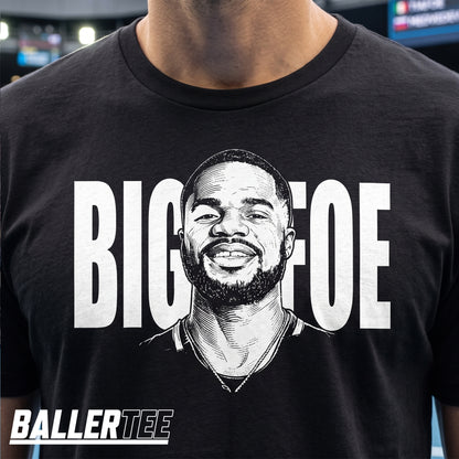 A close-up of a person wearing a black graphic T-shirt with a large white illustrated portrait and the text 'BIG FOE' across the chest. The brand name BALLERTEE appears in the lower-left corner.